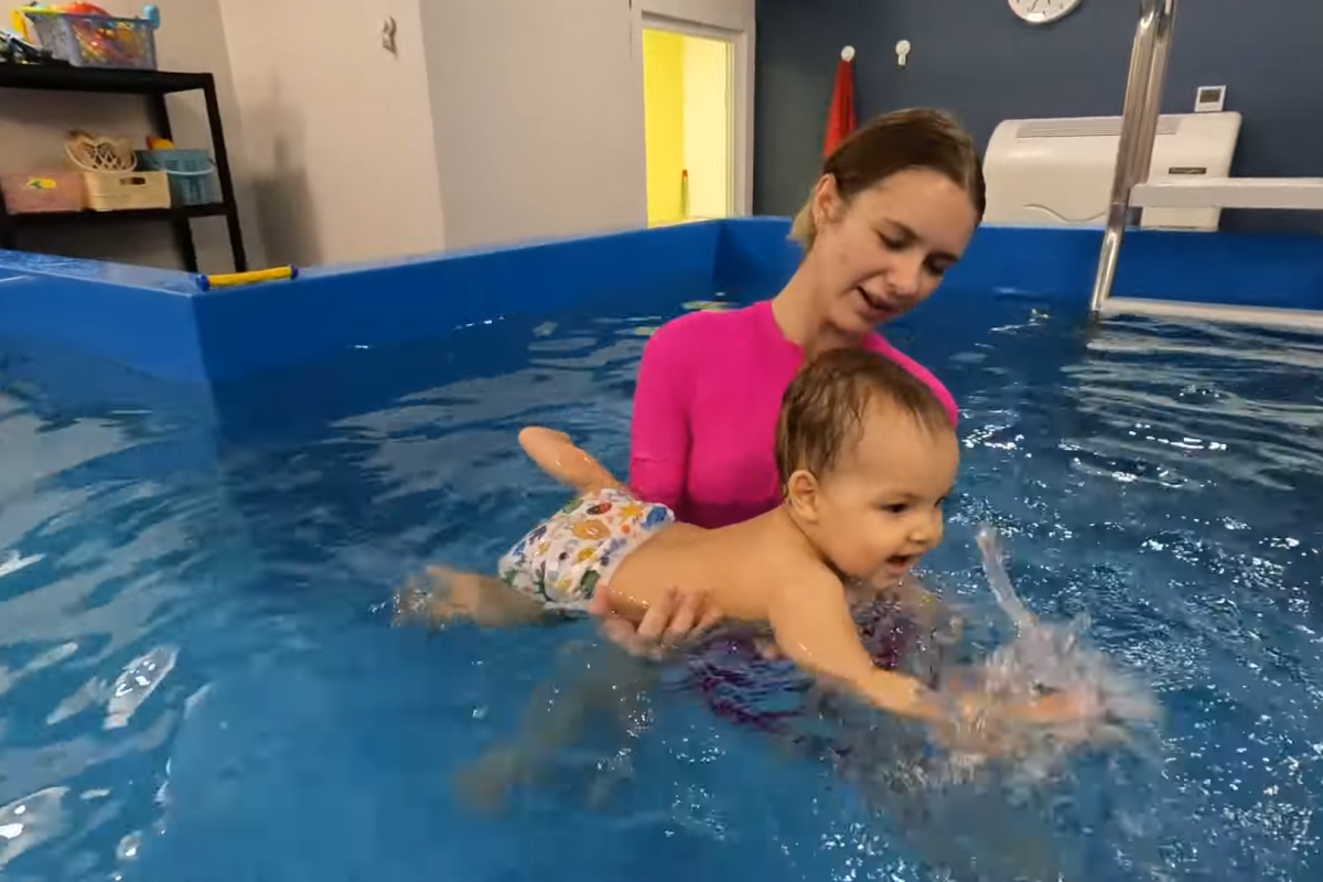 Certified swim instructor teaching water safety to a baby in a pool