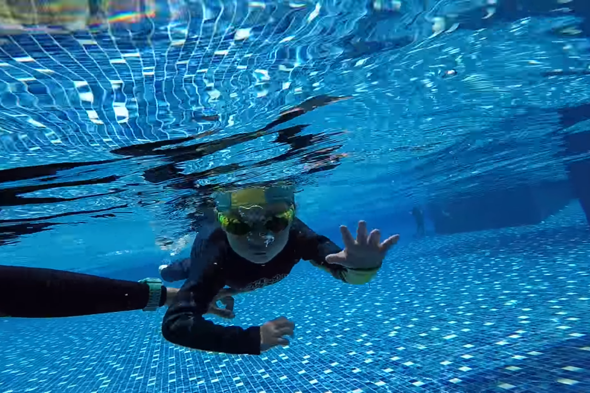 Young swimmer practicing water safety skills with an instructor during private swimming class